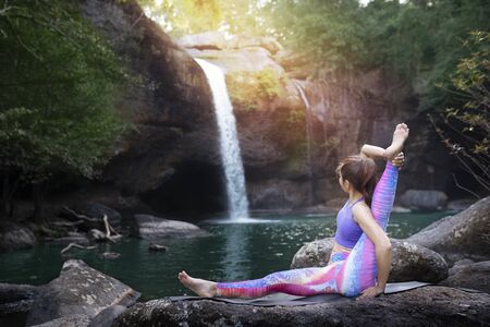 woman practice yoga in front of waterfall
