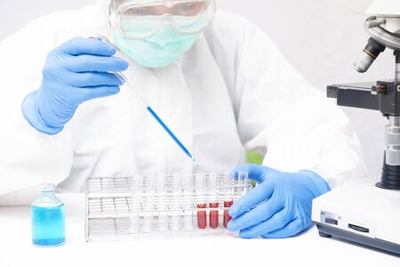 scientist or doctor working research in medical laboratory with microscope and test tube