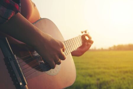 close up woman hand playing guitar  in grass field with sun light.の写真素材