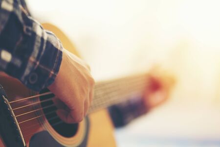 close up hand man playing acoustic guitar