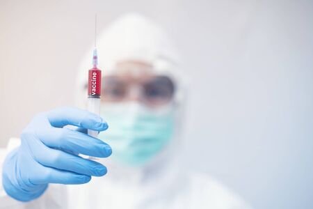 doctor in personal protective equipment or PPE. holding vaccine syringe,Coronavirus covid-19 outbreak conceptの写真素材