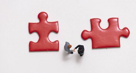 miniature people  shaking hand woth jig saw,business concept