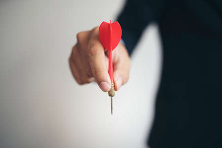 businessman hand holding dart arrow on dark backgroundの写真素材