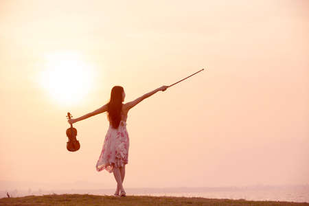 woman playing violin at sunset background