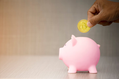 Hand putting gold coin to piggy bank on gray background. with copy space.Saving investment concept