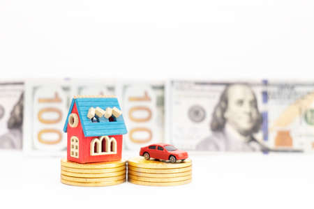 Car and house model on stack of coins with dollar banknote backgroundの写真素材