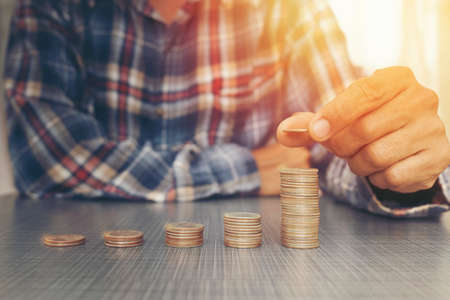Man hand putting coin dollar on money coin stack ,business conceptの写真素材