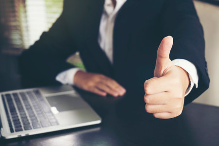 Business man shows thumb up while using laptopの写真素材