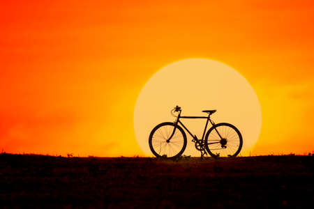 Silhouette of a bicycle with big sunの写真素材