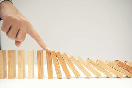 Close up businessman hand stop dominoes continuous toppledの写真素材