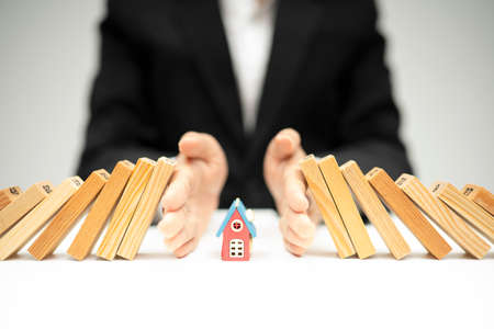 Businessman hand stop dominoes continuous toppled,insurance conceptの写真素材