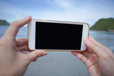 woman use smart phone take a photo of the sea in Prachuapkhirikhan ,thailand isolate black monitorの写真素材