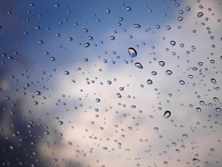 rain drop on a glass with blured a color of blue sky backgroundの写真素材