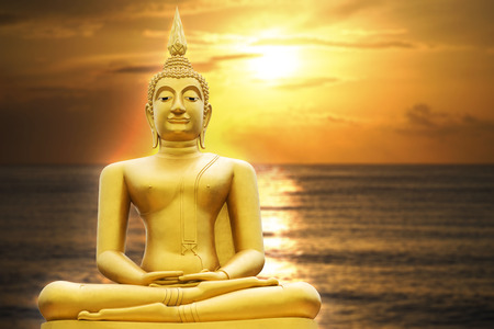 Gold image of Buddha in Blurred sunrise or sunset moment , with seascape, light effect added in back of image of buddha, prachuapkhirikhan,thailand,filtered imageの写真素材