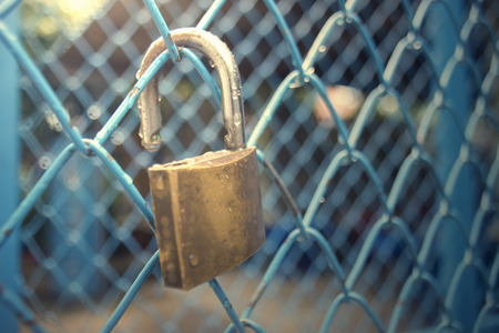 close up a key lock hook on iron wire gates and water drop of rain with blur background,selective focus,vintage filtered image,light effect addedの写真素材