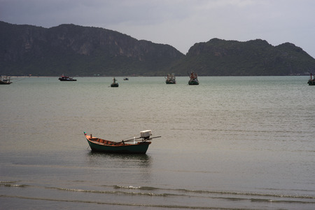 Traditional fishing  boat laying on a beach near the sea with big and long mountain in...