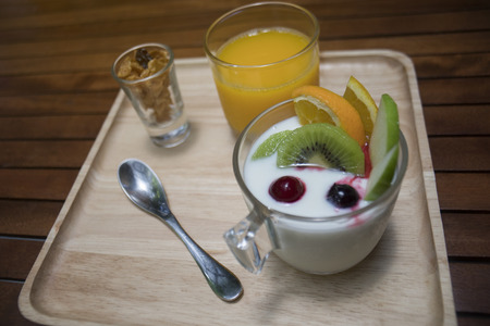 close up of  yogurt pudding in a glass with fruits decorate,honey conflake in a mug shot,orange juice in a glass on wooden plate,morning breakfast,diet and health conceptの写真素材