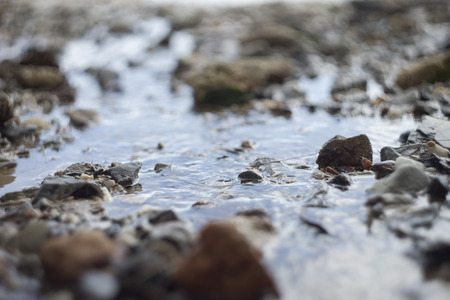 Close up of water rushing over rock beach.selective focusの写真素材