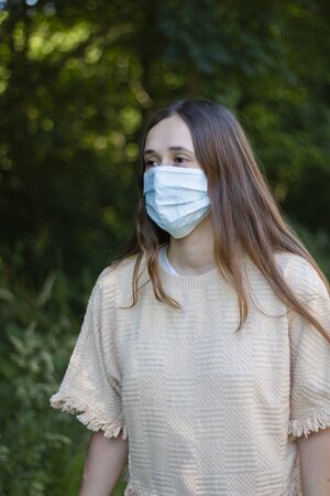 Woman walks through the garden with the mask on. Covid´19の写真素材