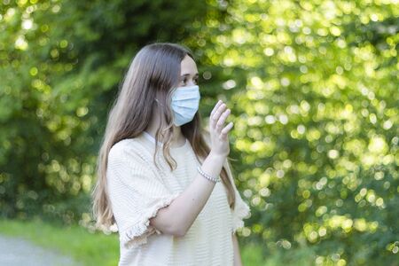 Woman walks through the garden with the mask on. Covid´19の写真素材