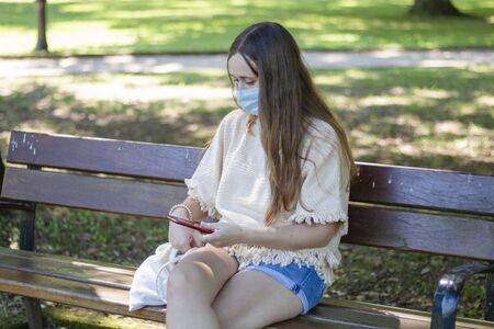 girl sitting on the street with face maskの写真素材