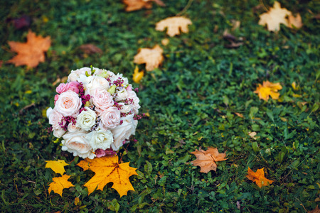 bridal bouquet lying on the green grass with maple leavesの写真素材