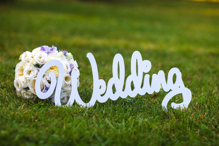beautiful bouquet and a white wooden sign wedding on grassの写真素材