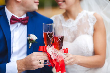Womans and mans wedding hands with glasses red wineの写真素材