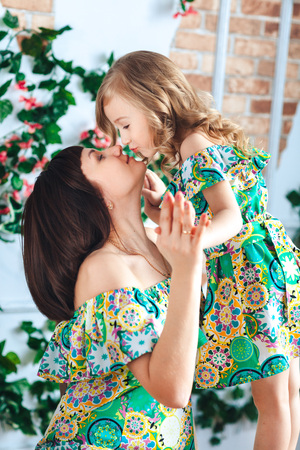 Little girl blonde in a bright dress kisses motherの写真素材
