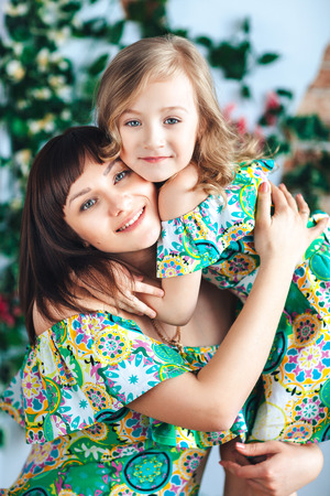 Close-up mother and daughter in a bright dress hugging and smilingの写真素材