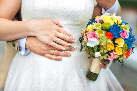 Bride hand with ring and wedding bouquet of flowersの写真素材