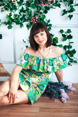 woman in a bright dress sits on the floor on a background of flowersの写真素材