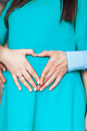 Female and male hand on the belly of a pregnant woman, close-upの写真素材