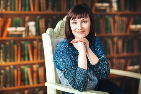 Portrait of a woman on the background of a bookshelfの写真素材