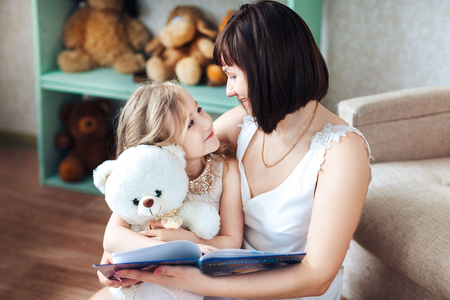 mother and daughter are sitting in the room reading a bookの写真素材
