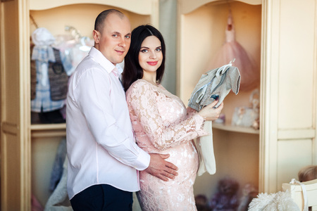 Husband and pregnant wife look at children's thingsの写真素材