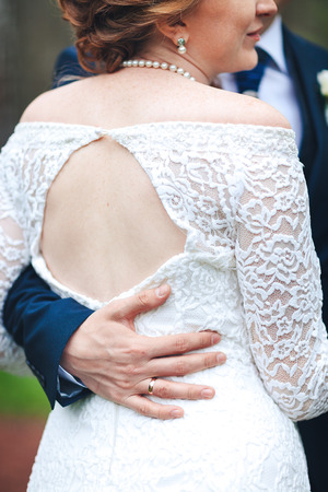 The bride groom's hand with a wedding ring hugs the brideの写真素材