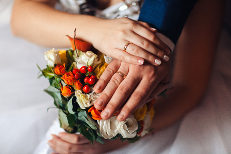 closeup, hands of bride and groom with wedding rings and bouquet