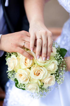 closeup, hands of bride and groom with wedding rings and bouquetの写真素材