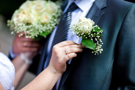 The bride's hand adjusts the buttonhole. weddingの写真素材