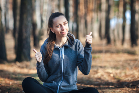 Young woman sitting on the grass in the forest on sunny dayの写真素材