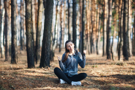 Young woman sitting on the grass in the forest on sunny dayの写真素材
