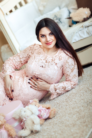 Portrait of a young pregnant woman lying on the floor in a children's roomの写真素材