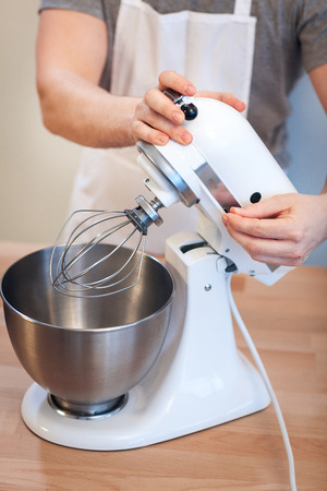 A man is beating an egg cream with a mixer, close-up of a hand include a mixerの写真素材