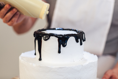 Cream white cake poured with chocolate glaze, close-up,の写真素材