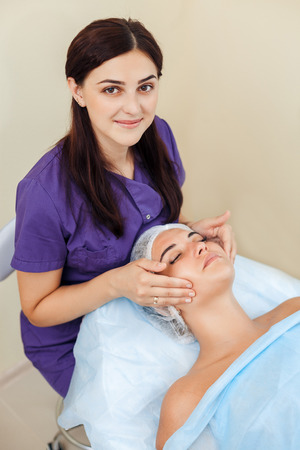 Cosmetologist Applying cream to the face and massages woman. Cosmetic procedures Mechanical cleaning of the face. Cosmetology.の写真素材