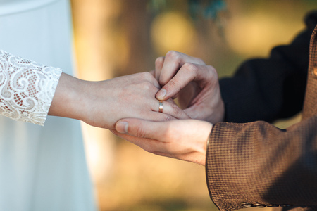The hands of the newlyweds. A man's hand puts on a ring. wedding ceremony.の写真素材