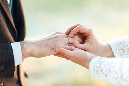 The hands of the newlyweds. A womens's hand puts on a ring. wedding ceremony.の写真素材