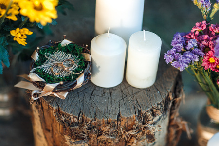 rings lie on a stump decorated with candles and flowers in rustic styleの写真素材