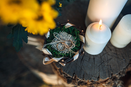rings lie on a stump decorated with candles and flowers in rustic style